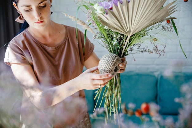 Una florista caucásica venda un ramo con una cuerda en su estudio de flores