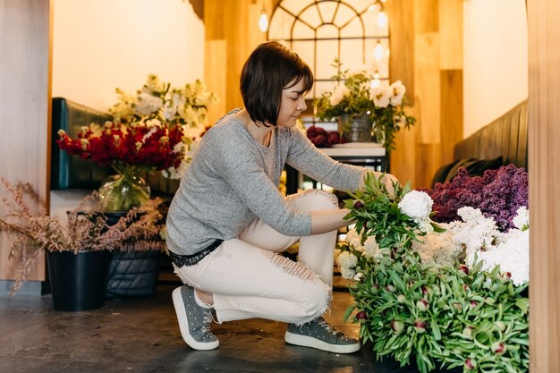 Florista colhendo flores para um buquê em uma floricultura