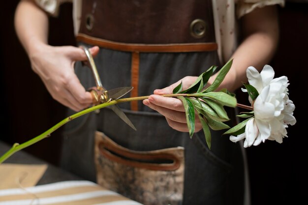 Florista cortando o caule de uma flor branca