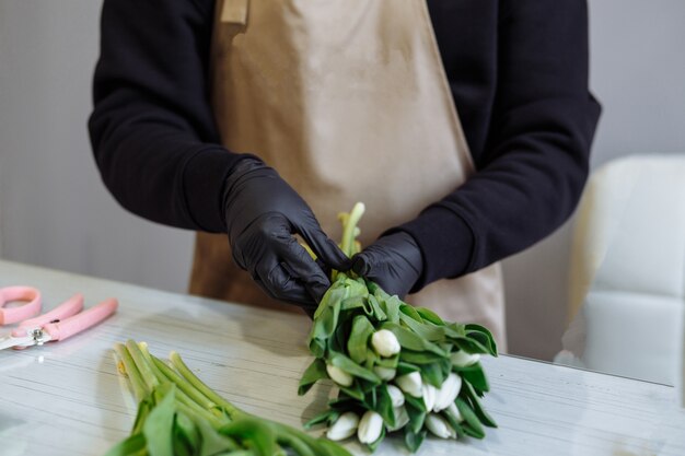 Florista crea un ramo de tulipanes blancos en una florería