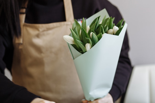 Florista crea un ramo de tulipanes blancos en una florería