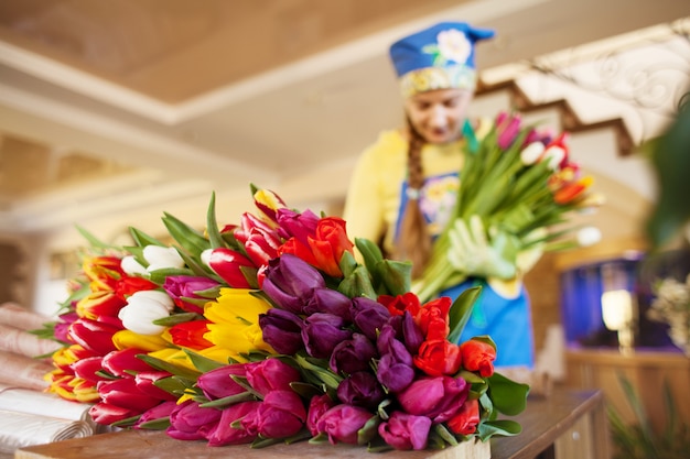 Florista da menina está embalando lindas tulipas em uma loja de flores em papel kraft