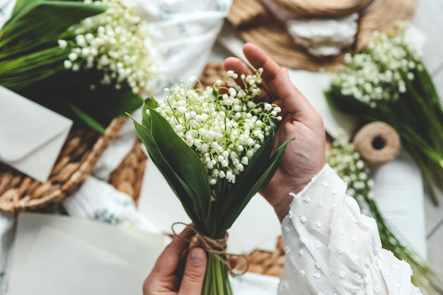 Florista de menina tem um buquê de lírios do vale nas mãos