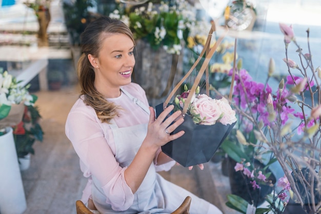 Florista de mulher atraente no avental segurando uma tesoura e flores de fixação