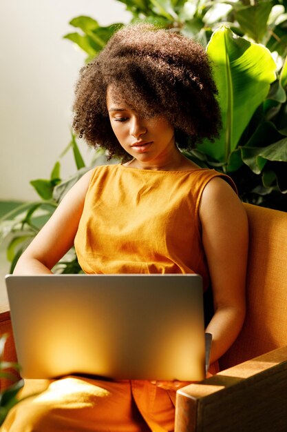 Florista femenina sentada en su taller y leyendo desde la computadora portátil