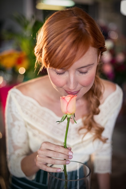 Florista feminina cheirando uma flor rosa