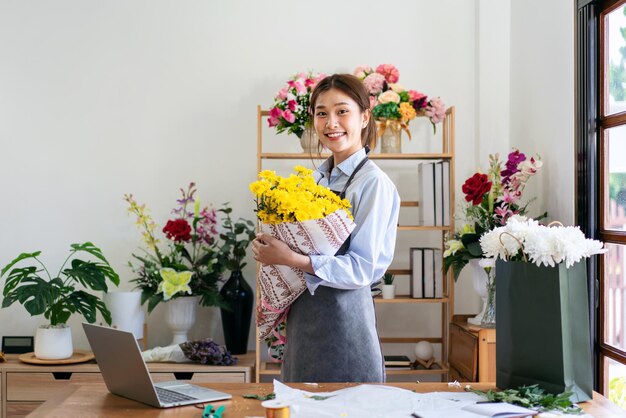 Foto florista feminina em avental segurando buquê de crisântemo amarelo wra