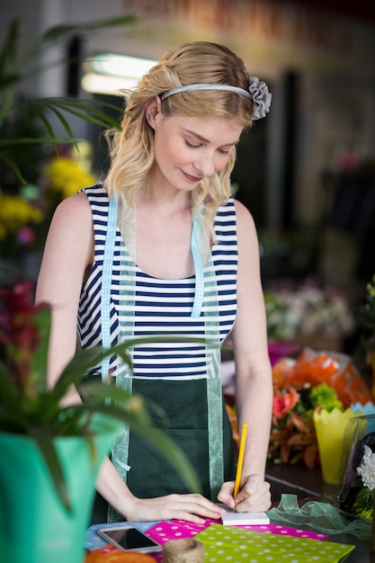 Florista feminina escrevendo em um bloco de notas