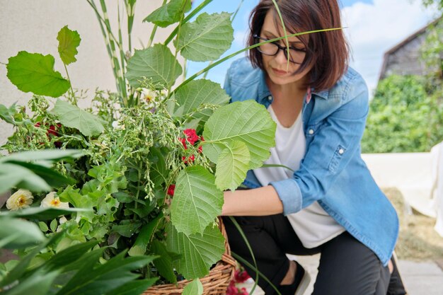 Florista feminina fazendo arranjo floral ao ar livre fluxo de trabalho de criação de cesta de flores