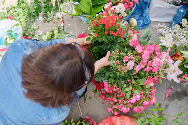 Florista feminina fazendo arranjo floral ao ar livre fluxo de trabalho de criação de cesta de flores