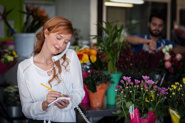 Florista feminina, pegando um pedido no telefone