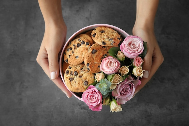 Florista feminina preparando a caixa com lindas flores e biscoitos, closeup