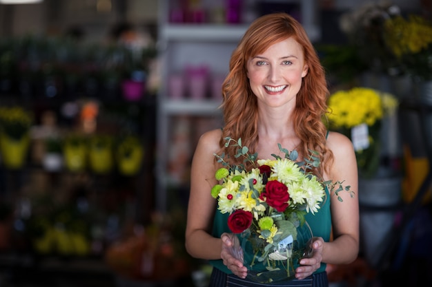 Florista feminina segurando o vaso de flor na loja de flores