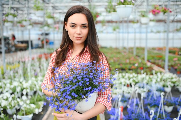 Florista feminina trabalhando em sua loja de flores cercada por plantas