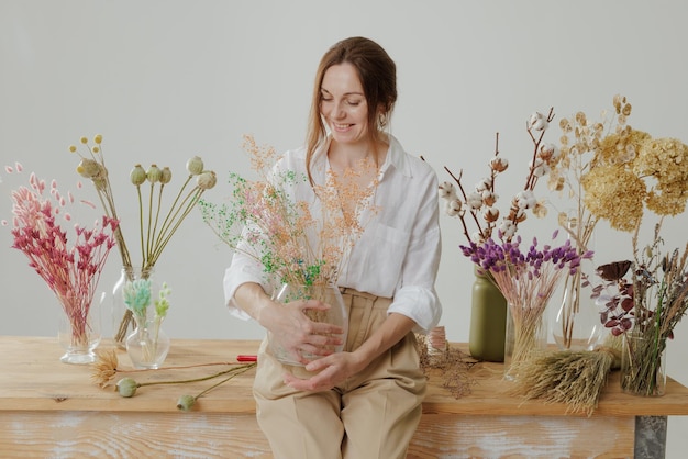 Una florista hace un ramo eterno de flores secas en una mesa de madera en su taller