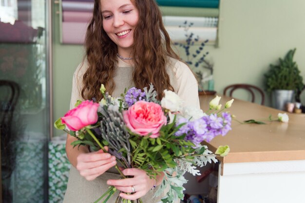 Florista jovem trabalhando com flores no local de trabalho conceito de pequena empresa, estilo de vida, retrato recortado, flores, close-up
