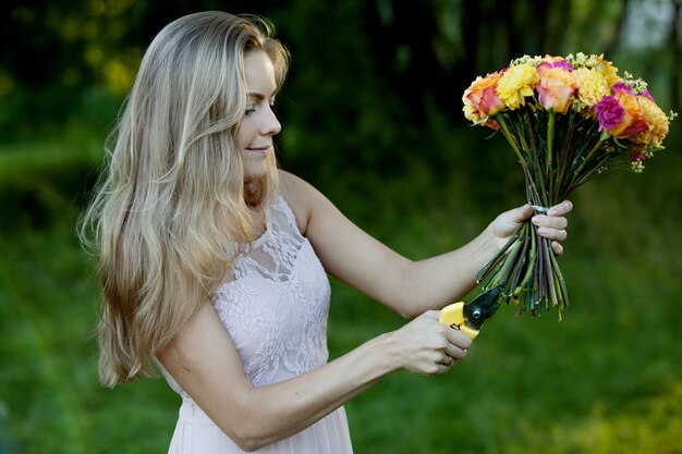 Florista linda jovem mulher. A garota no parque desenha um buquê. Exterior