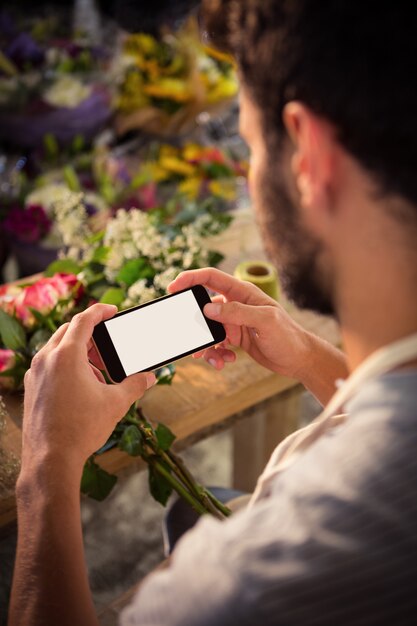 Florista masculino tomando fotografía de ramo de flores