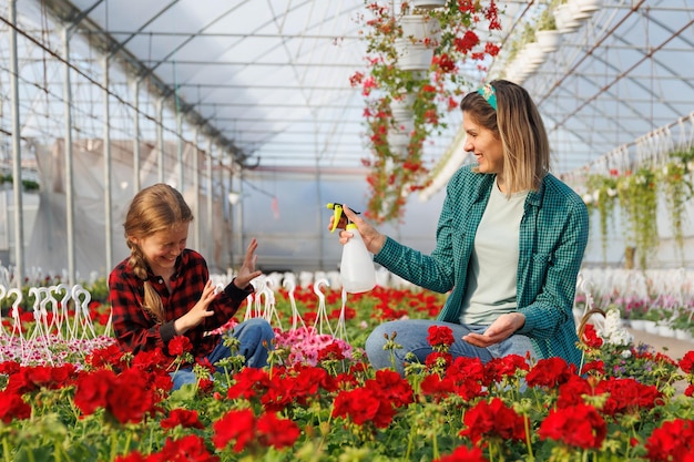 Foto florista y niña su hija se divierten madre feliz rociando a su hija con agua