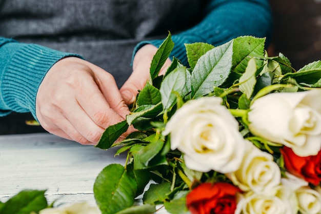 Florista no trabalho faz um elegante buquê moderno de flores diferentes