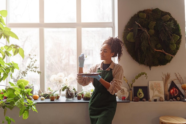 La florista profesional examina las plántulas en el concepto de jardinería de estudio floral