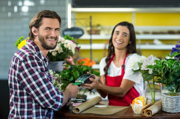 Florista recebendo pagamento por cartão de crédito do cliente na floricultura