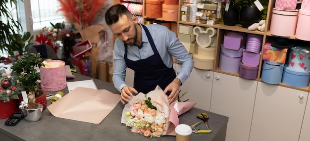 El florista recoge un delicado ramo de rosas como regalo para el día de san valentín en boutiques de