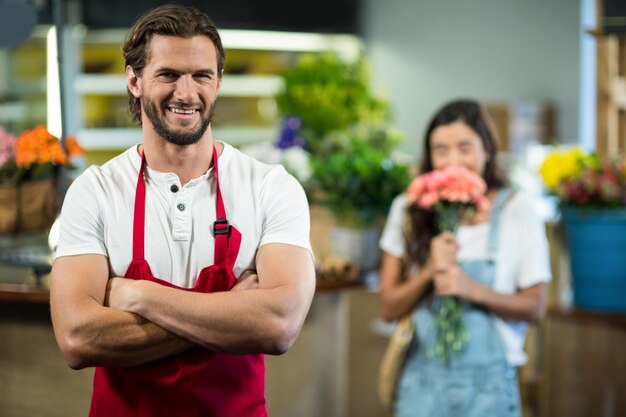 Florista sorridente em pé na floricultura com os braços cruzados