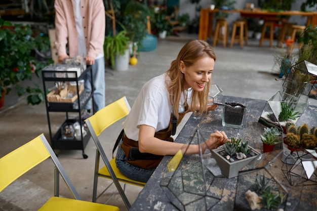 Florista sorridente feliz fazendo composição de plantas suculentas