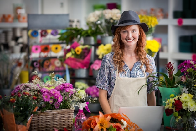 Florista sorridente usando laptop na loja de flores