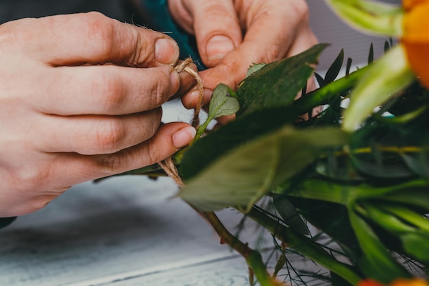 El florista en el trabajo hace un moderno y moderno ramo de flores diferentes