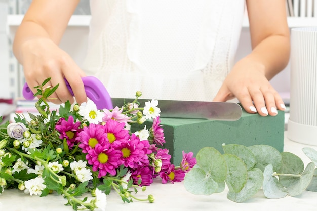 Florista trabalhando em uma floricultura menina florista corta oásis com uma faca empresa de floricultura cursos de floricultura