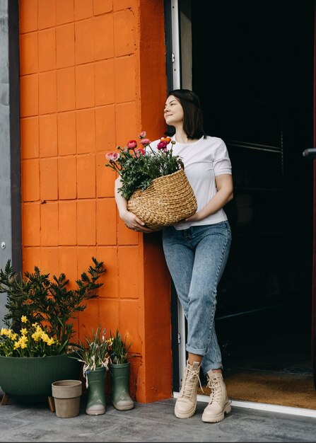 Foto florista trabalhando em uma floricultura mulher uma cesta grande com flores cor de rosa