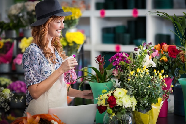 Floristas de pulverização de água em flores na loja de flores