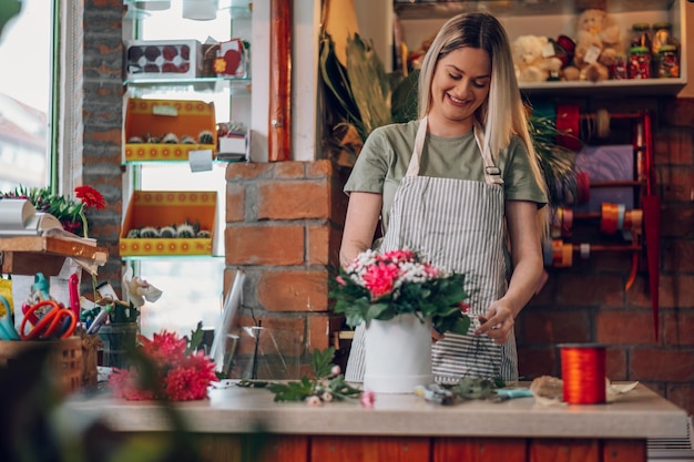 Floristenfrau, die Blumenarrangements in einer runden Schachtel erstellt