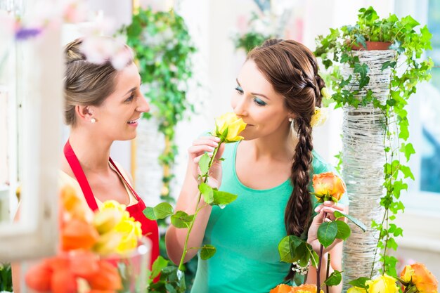 Floristenfrau, die rosafarbenen Blumenstrauß an ihren Kunden verkauft