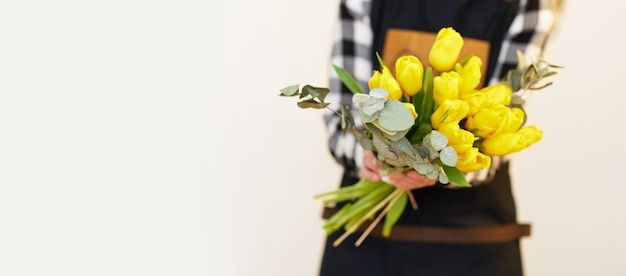 Floristenfrau, die schönen Blumenstrauß von frischen gelben Tulpen hält. Platz kopieren. Blumenlieferung