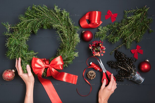 Floristenhände, die Weihnachtskranz machen