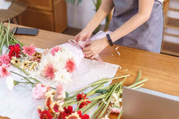 Floristenkonzept Floristin wickelt und kreiert farbenfrohen Blumenstrauß mit Papier und Schleife