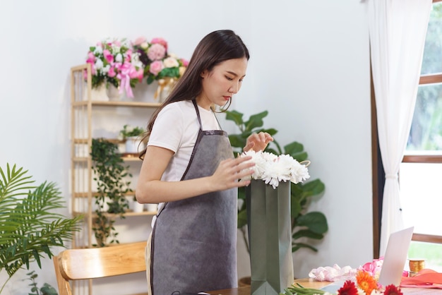 Floristenkonzept Weibliche Floristin arrangiert Chrysanthemenblumenstrauß in der Einkaufstasche im Geschäft