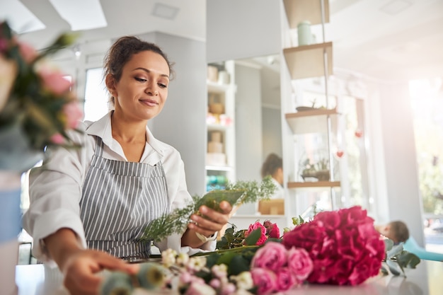 Floristería femenina concentrada eligiendo flores para creaciones florales