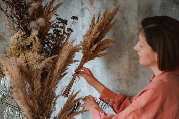 Floristería femenina decora un ramo eterno de flores secas en el mostrador de su Flower Studio