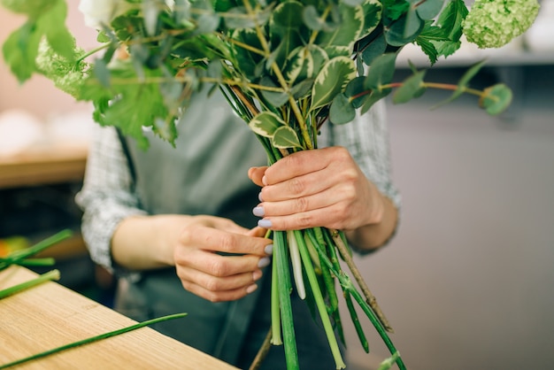 Floristería femenina en delantal tiene composición de flores en la mano