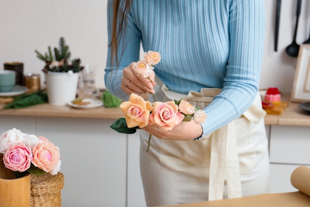 Floristería femenina haciendo ramo de hermosas flores de primavera en la mesa de madera clara