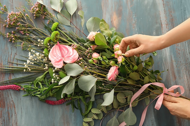 Foto floristería femenina preparando ramo de flores hermosas en la mesa