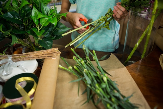 Floristería femenina recortando tallo de flor