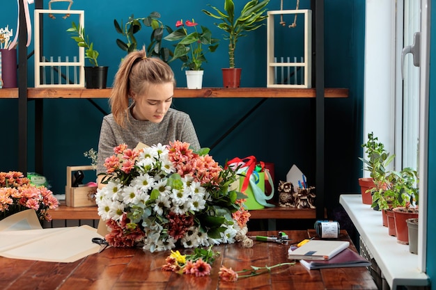 Foto floristería hace un ramo de crisantemos multicolores una joven adulta trabaja con entusiasmo