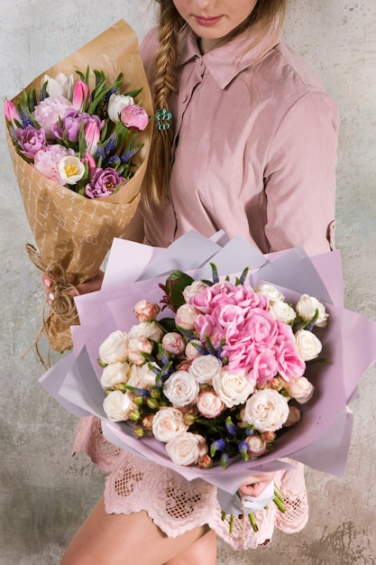 Floristería irreconocible mostrar ramos de flores de rosas y tulipanes. Mujer joven con un ramo de rosas. Taller florístico, habilidad, decoración, pequeña empresa, concepto de regalo