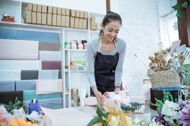 Floristería joven que trabaja en la tienda de flores hacer pedido de flores de franela en una mesa