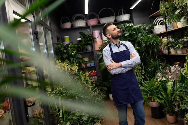 Floristería masculina con delantales azules en una tienda de flores y ramos de flores.